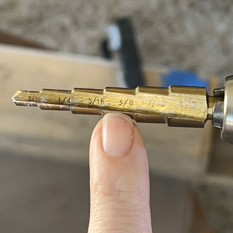 step drill bit with finger pointing to 3/8 mark